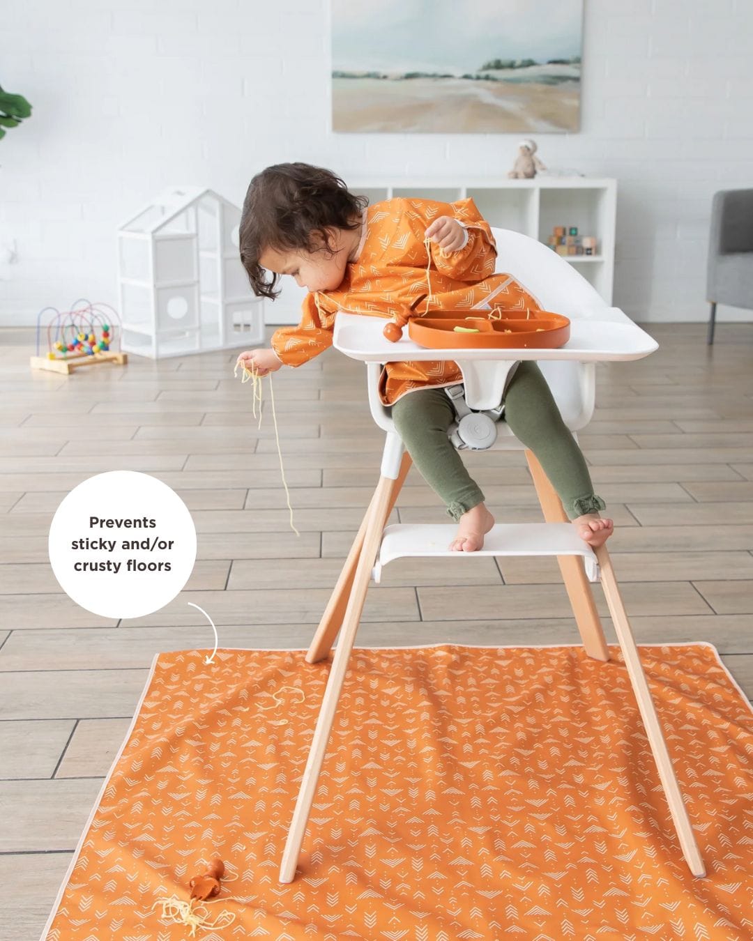 baby in high chair dropping food on a splat mat