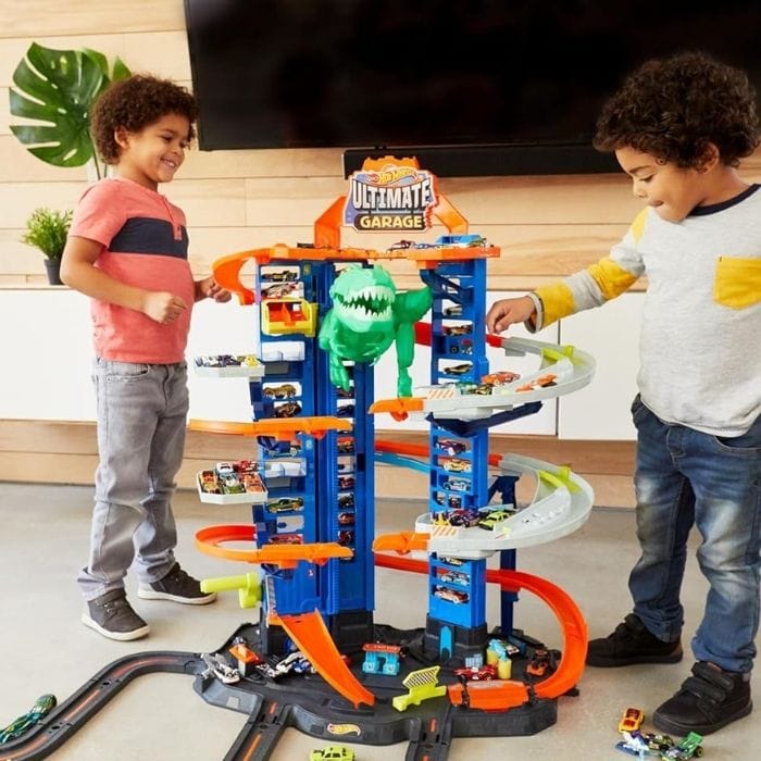 two kids playing with a hot wheels track and cars