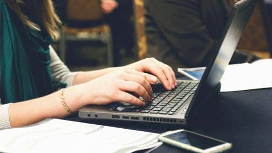 up close of a woman's hands typing on a laptop looking for pregnancy tools.