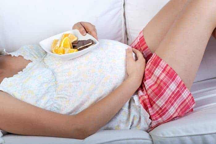 7 Things Every Pregnant Woman Should Do, At Least Once. Pregnant woman eating oranges and chocolate.
