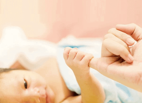 newborn baby holding the finger of mother after giving birth