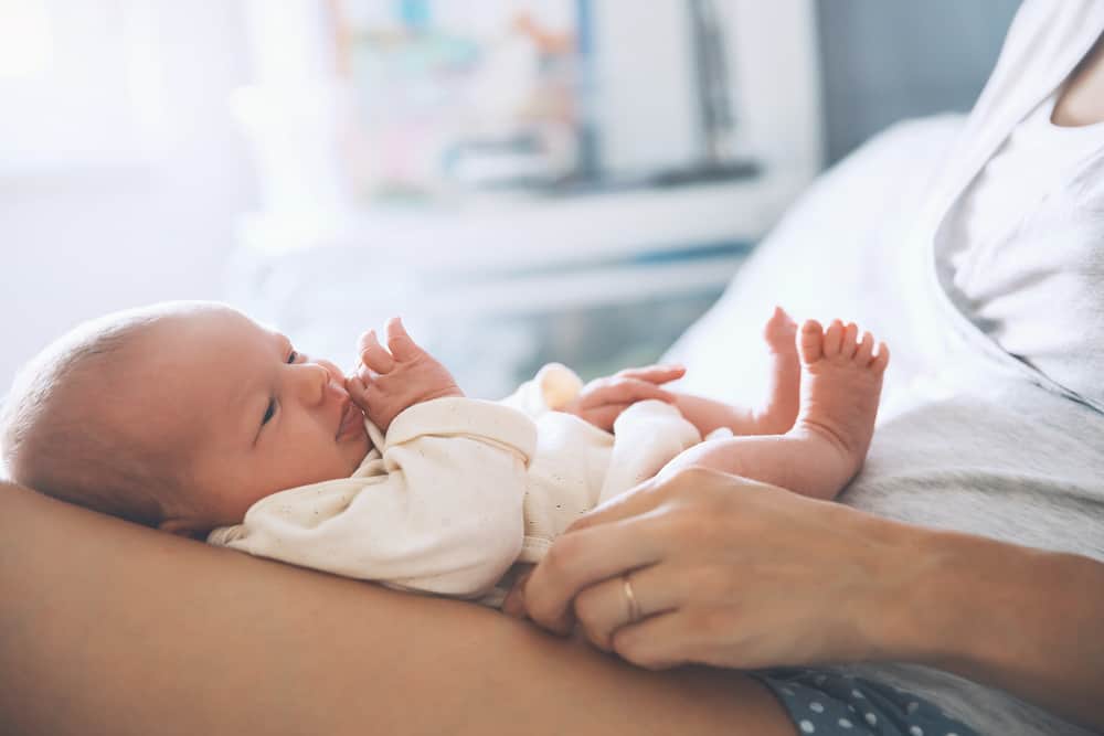 Mom holding new baby on her lap learning to adjust to life as a new mom