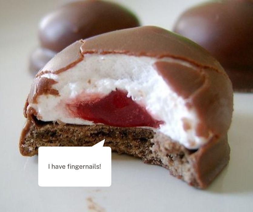 A chocolate-covered marshmallow treat with a red jelly center and a text bubble that says, I have fingernails!