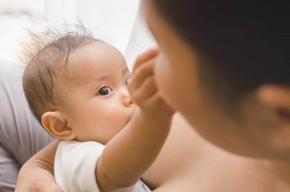 Close-up of a baby looking up while breastfeeding.