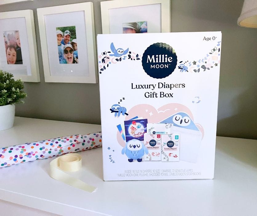 Millie Moon Luxury Diapers Gift Box sitting on a table next to polka dot wrapping paper and cream ribbon.
