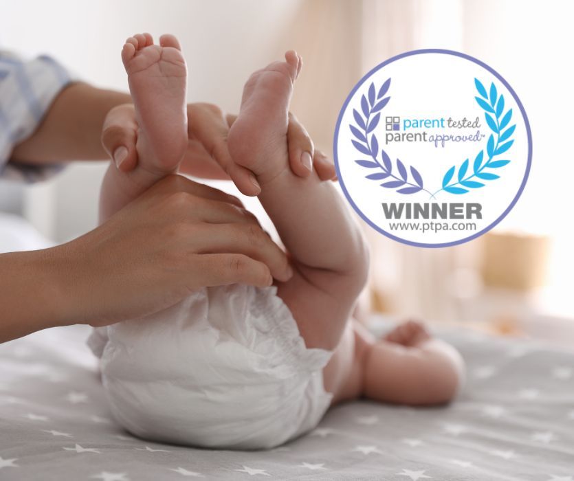A parent's hands changing a baby's diaper, with the Parent Tested Parent Approved Winner logo.