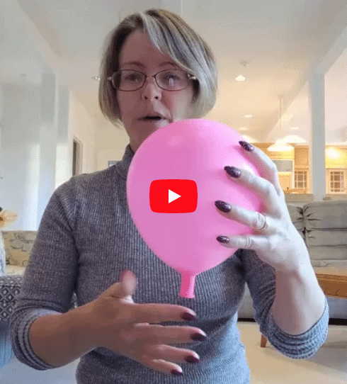 A woman wearing glasses and a grey sweater holds a pink balloon over her hand. A red play button icon is in the center.