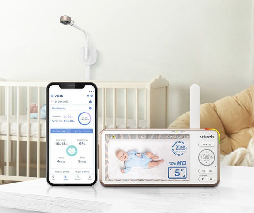 VTech smart baby monitor with 5-inch parent unit, smartphone showing sleep analytics, and wall-mounted camera over a crib.