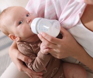 A baby drinks formula from a bottle while being held, illustrating gentle formula choices for sensitive babies after feeds.