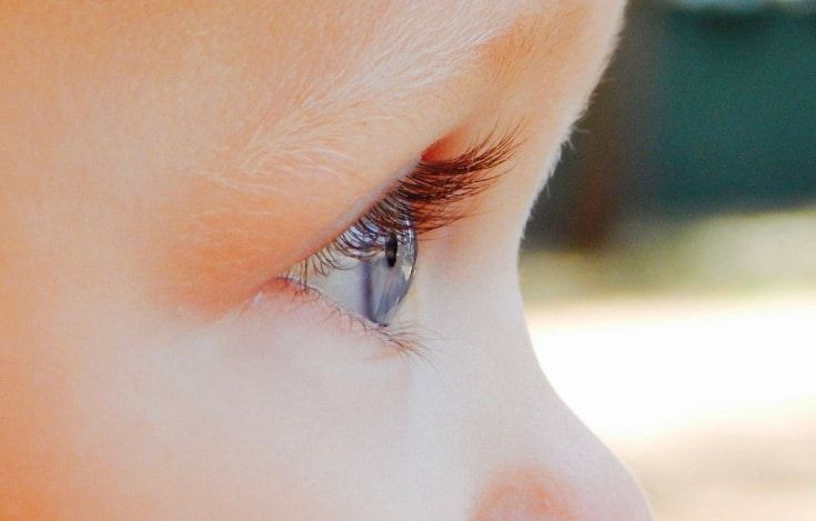 Close-up profile of a baby's blue eye and long eyelashes.