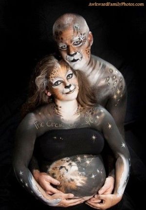 A man and pregnant woman with leopard-themed body paint. A lion cub is painted on the woman's belly.