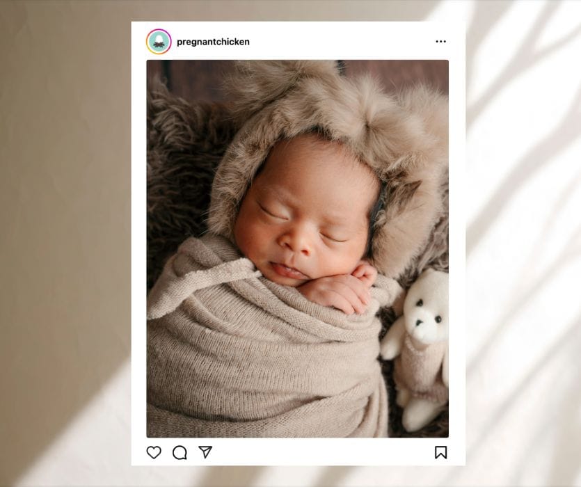 Sleeping newborn in a brown swaddle and faux fur bear hat next to a small teddy bear in an Instagram post.