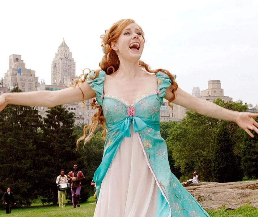 Amy Adams as Giselle in a teal dress, singing with her arms outstretched in Central Park.