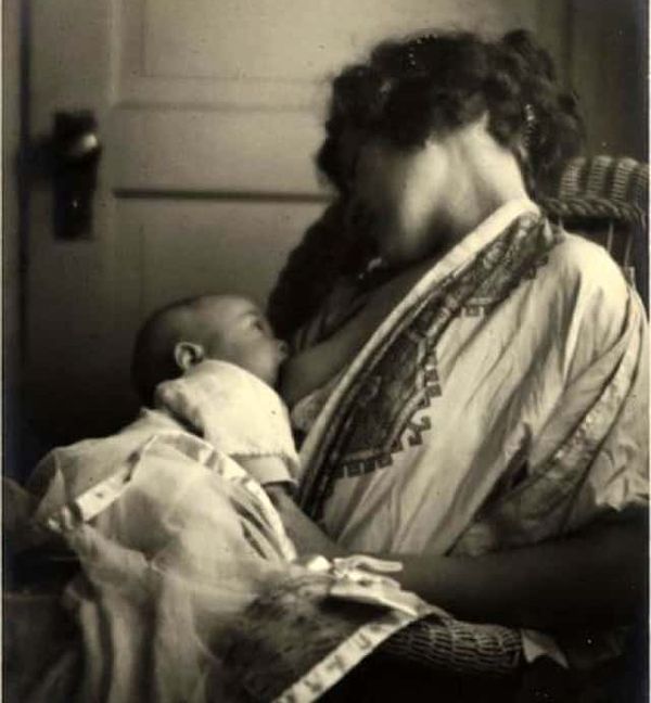 Vintage black and white photograph of a woman with dark hair breastfeeding an infant.
