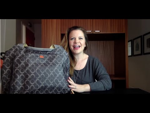 A woman smiling next to a grey and black patterned PacaPod diaper bag.