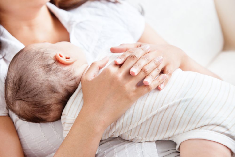 Close-up of a person holding a sleeping baby close to their chest.