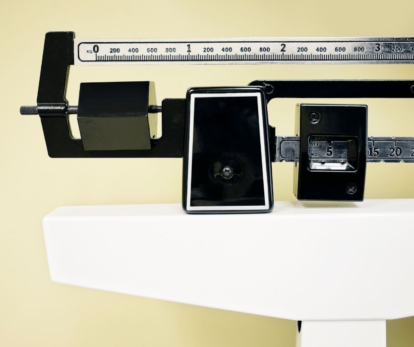 Close-up of a mechanical physician beam scale showing the sliding weights and kilograms measurement ruler.