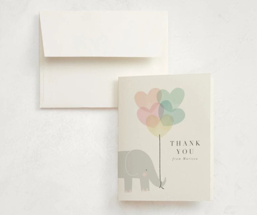 Baby shower thank you card featuring a gray elephant holding pastel heart-shaped balloons next to a white envelope.