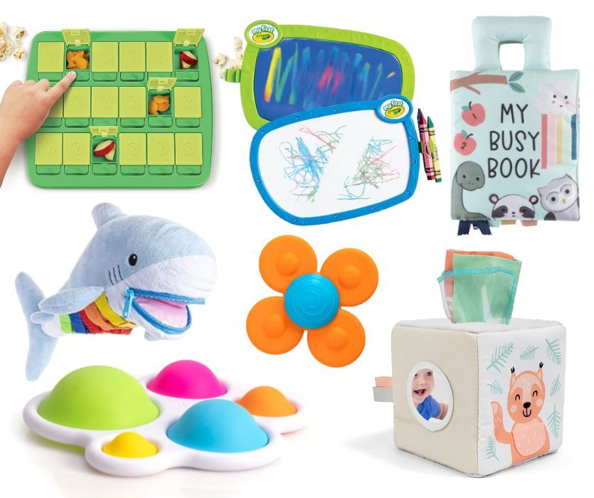 A collection of travel toys including a snack spinner, drawing boards, soft books, fidget toys, and a plush shark.
